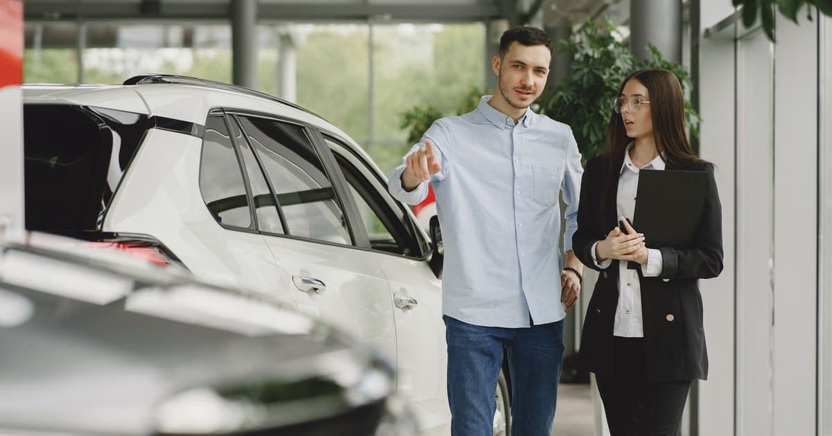 Vendedora de una concesionaria mostrando un auto a un cliente en el salón
