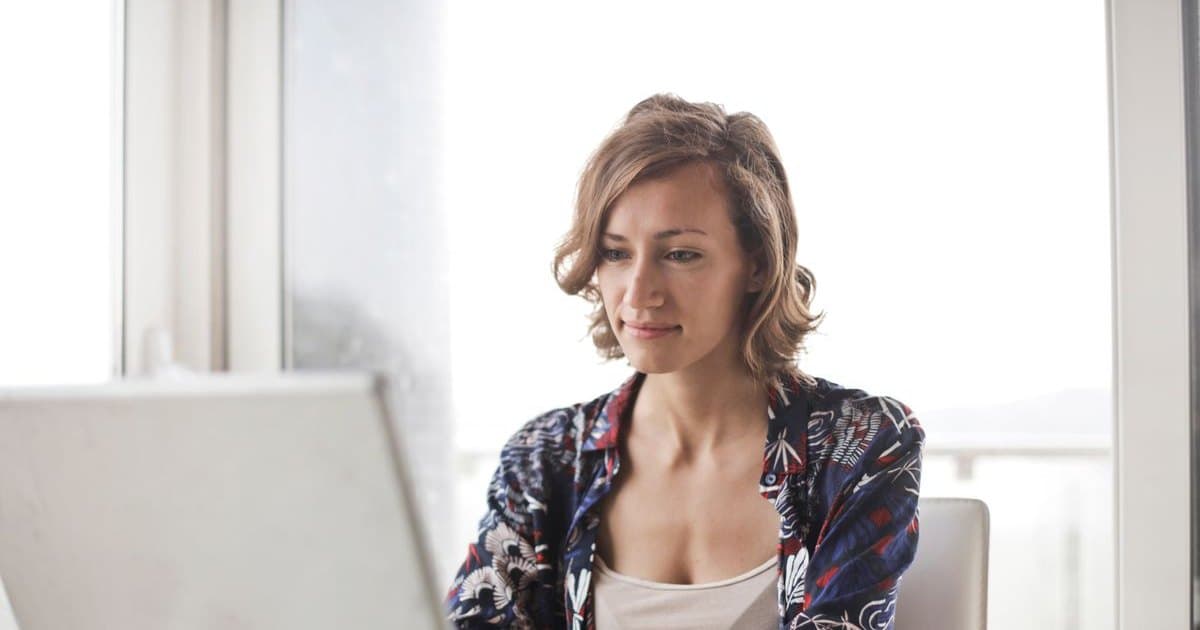 Mujer trabajando con su notebook junto a una ventana