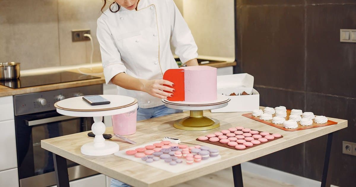 Pastelera decorando una torta en el obrador